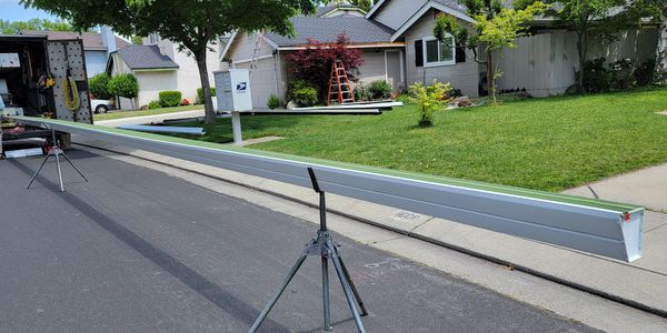 Long metal beam balanced on a tripod on a residential street.