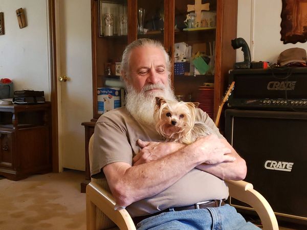 A man holding a small dog and sitting