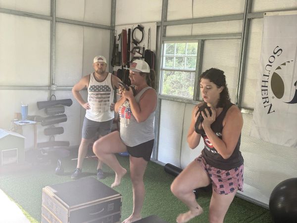 Three people doing step exercises in a gym.
