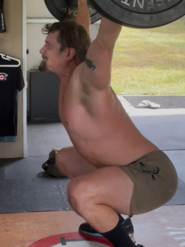 Man performing an overhead squat with a barbell.