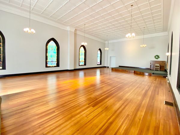 Empty room with wooden floor and stained glass windows.