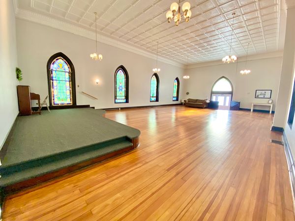 Spacious room with stained glass windows and wooden floor.