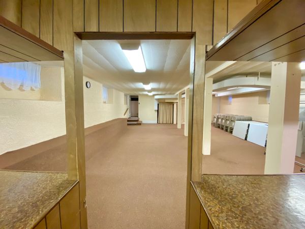 Empty multi-purpose room with brown carpet and wood paneling.