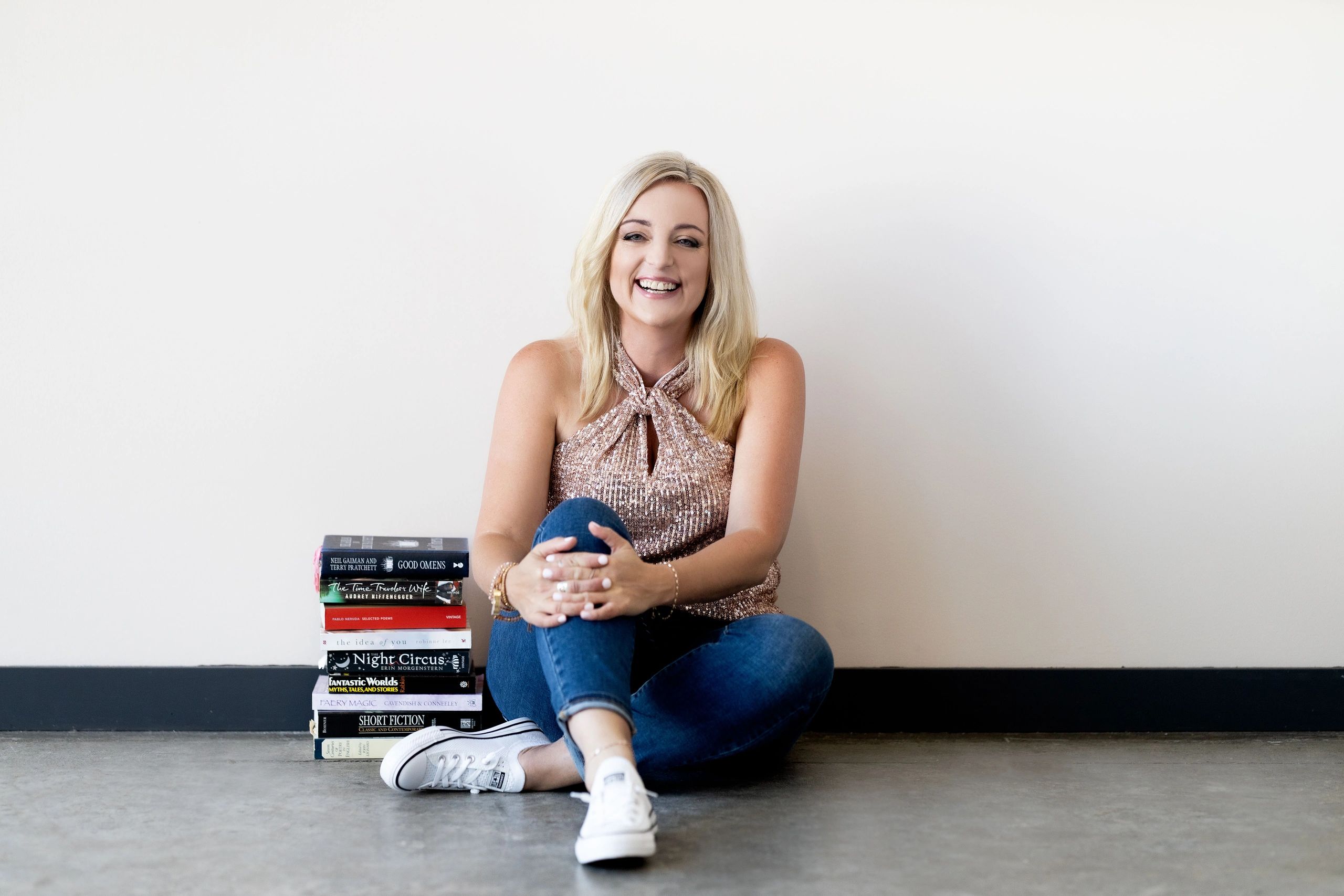 Ruth Fae - Intuitive Writing Coach, Editor & Author sitting on the floor with a stack of books.