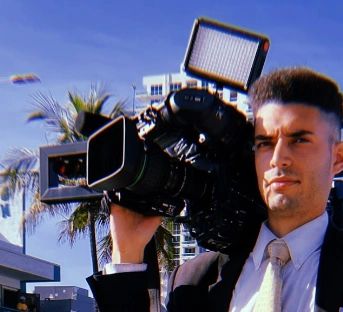 News reporter with camera covering a car accident story in Pompano Beach, FL