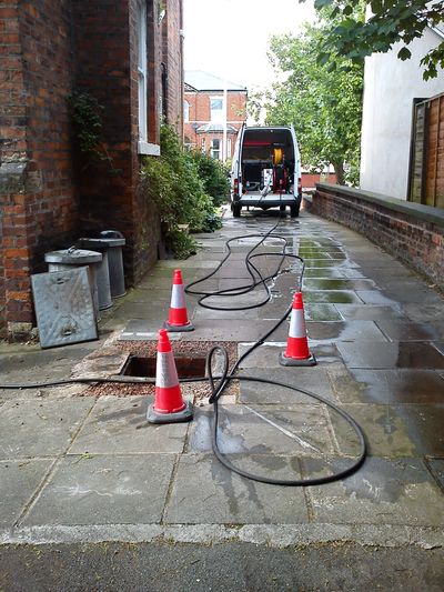 Accessing manhole to clear a blocked drainage system, using the high-pressure water jetting machine.