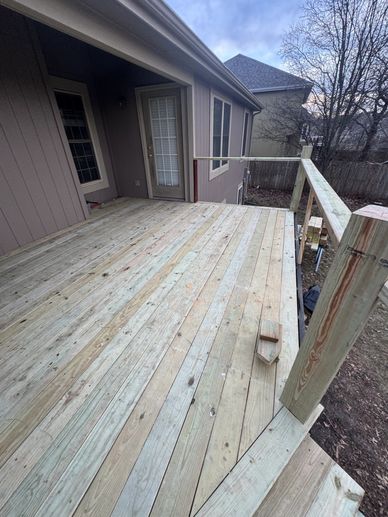 New wooden deck attached to a house under cloudy sky.