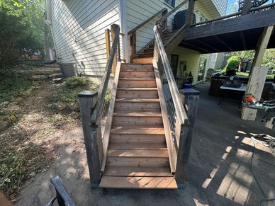 Wooden outdoor stairs leading to a house deck.