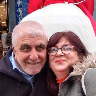 Smiling older couple posing outdoors in winter clothing.