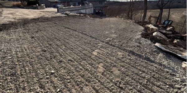 Gravel driveway with tire tracks near rural houses.