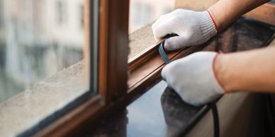 Person installing window weatherstripping with gloves.