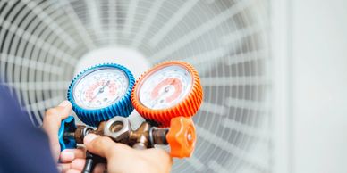 Man adjusting HVAC gauges in front of an air conditioning unit.