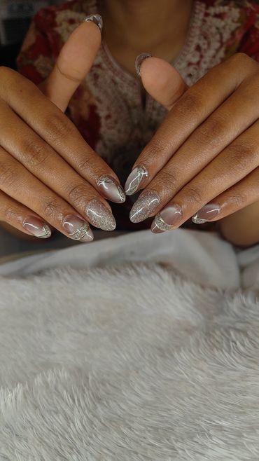 Elegant manicured nails with intricate silver designs.