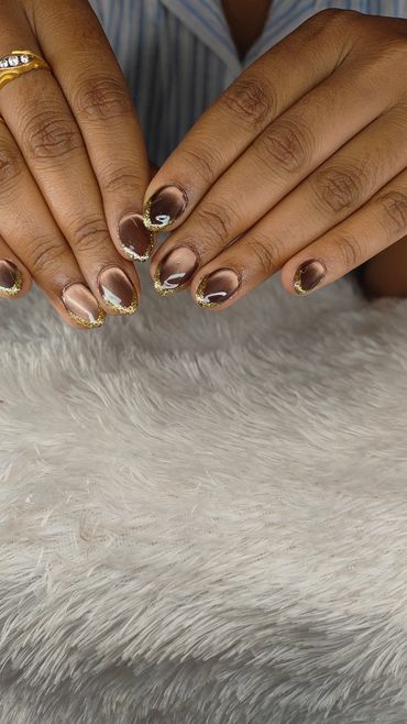 Hands with brown and gold glitter nail art.