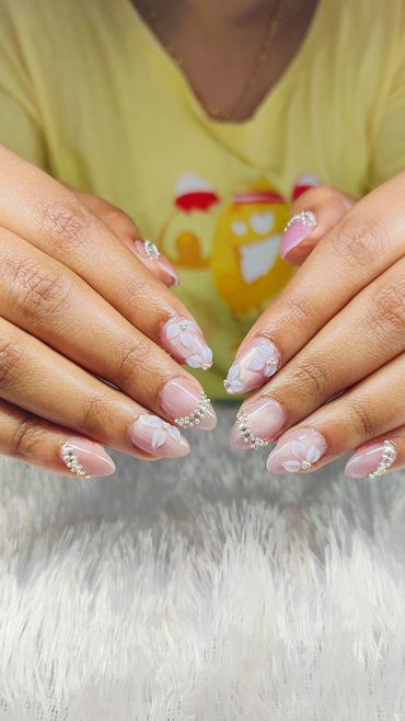 Elegant floral and rhinestone nail art on natural nails.
