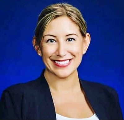 Smiling woman in business attire against a blue background.
