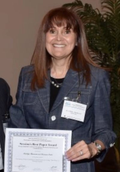 Woman smiling while holding an award certificate.