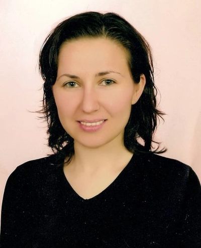 Portrait of a woman with dark hair and a black top smiling softly.
