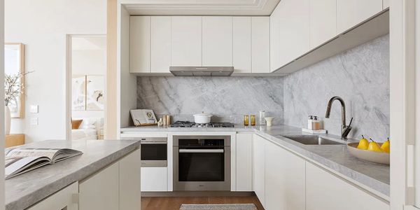 Modern white kitchen with marble backsplash and grey countertops.