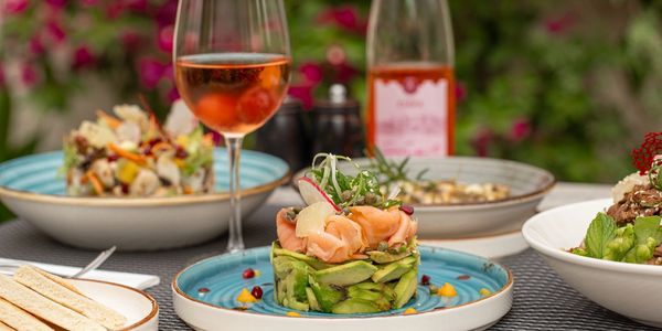 Elegant plated seafood appetizer with a glass of rosé wine on an outdoor table.