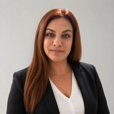 Professional woman in a black blazer and white blouse smiling confidently.