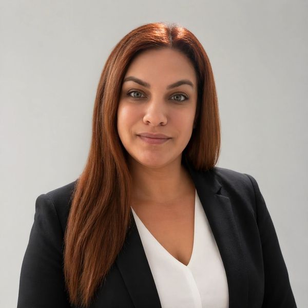 Professional woman in a black blazer and white blouse smiling confidently.