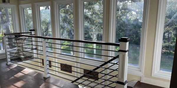 Modern black and white staircase railing by large windows.