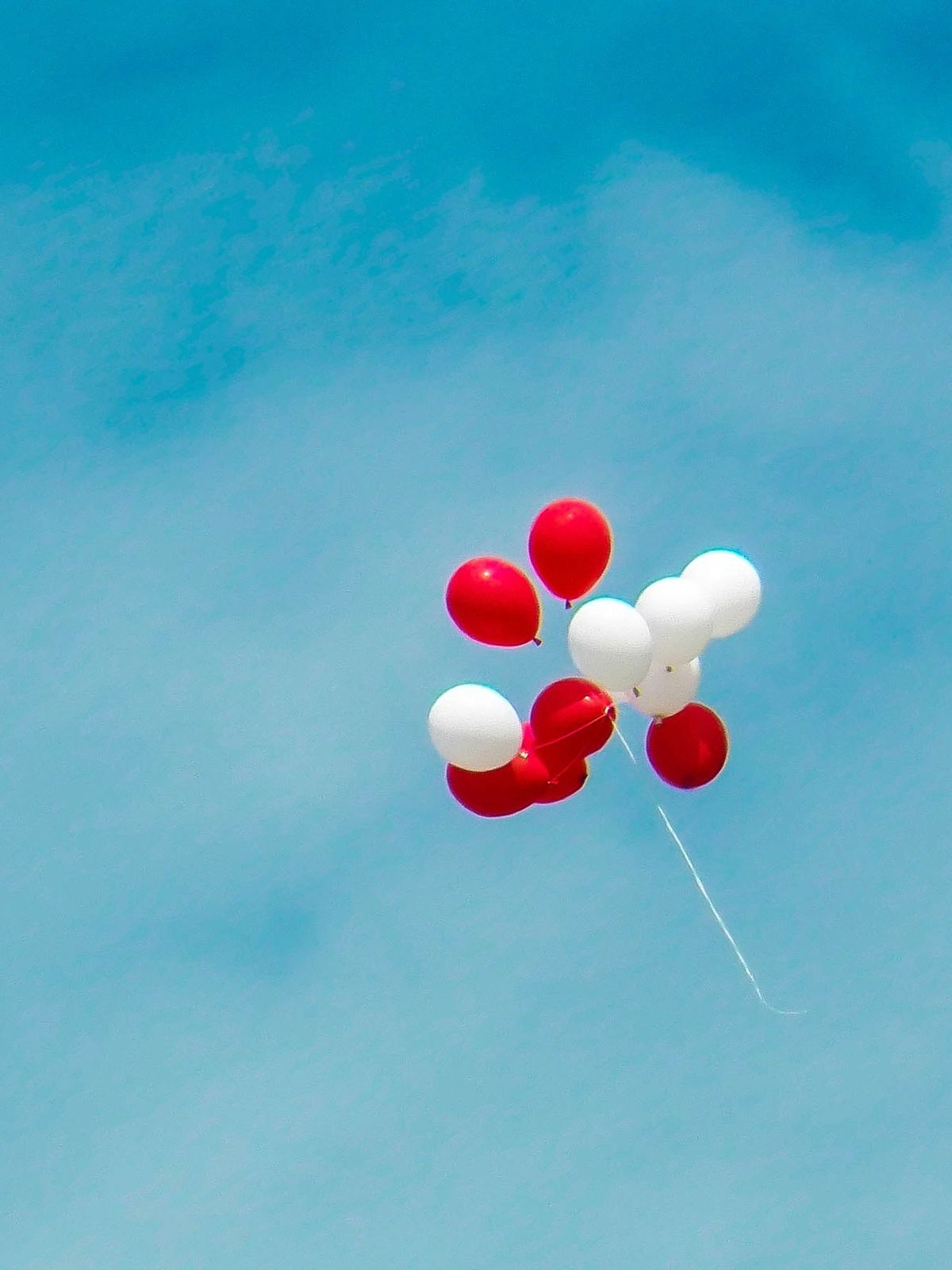 Red and white balloons floating in the sky.