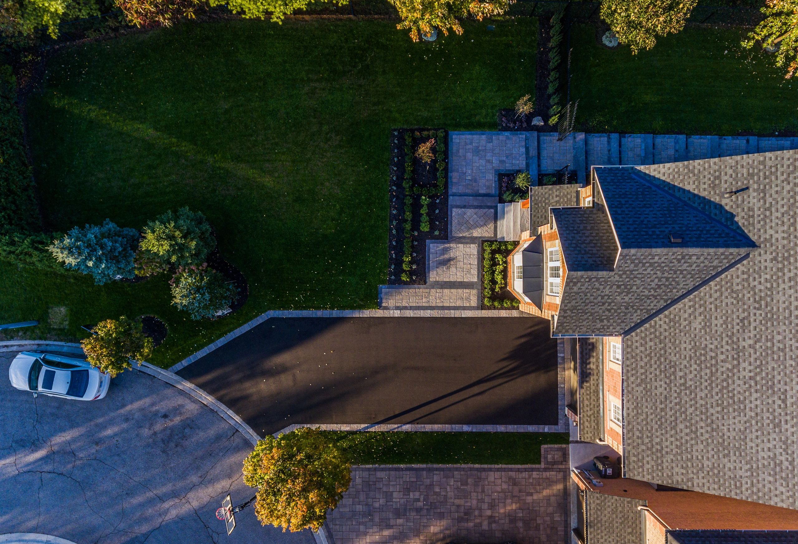 Aerial view of a house with driveway and parked car.