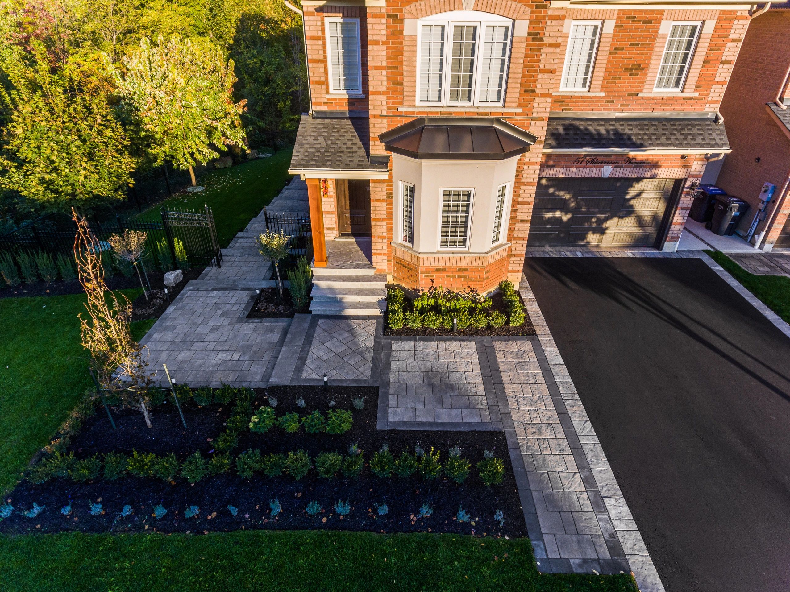 Front yard and entrance of a brick house with a paved driveway and walkway.