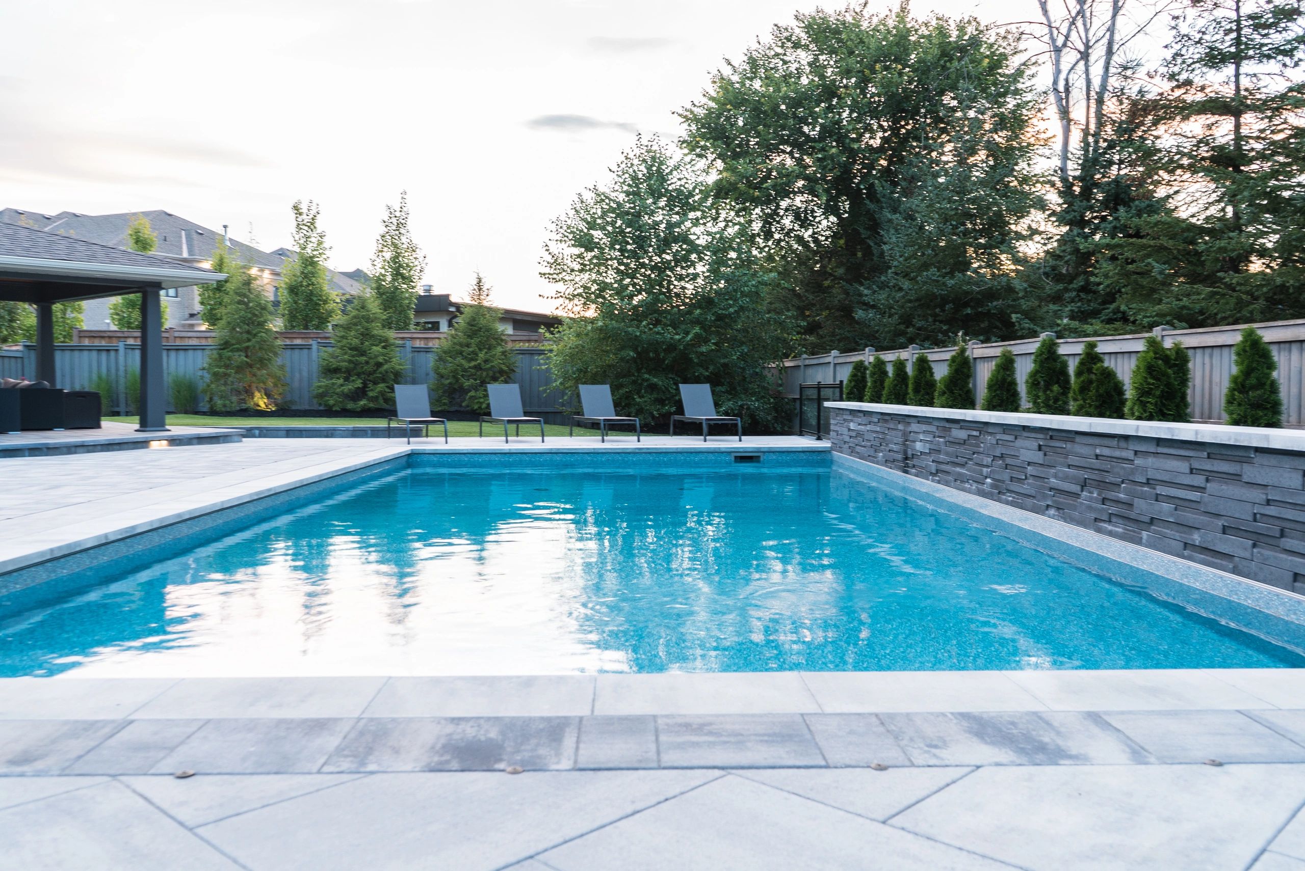 Modern backyard with a clean swimming pool and lounge chairs.