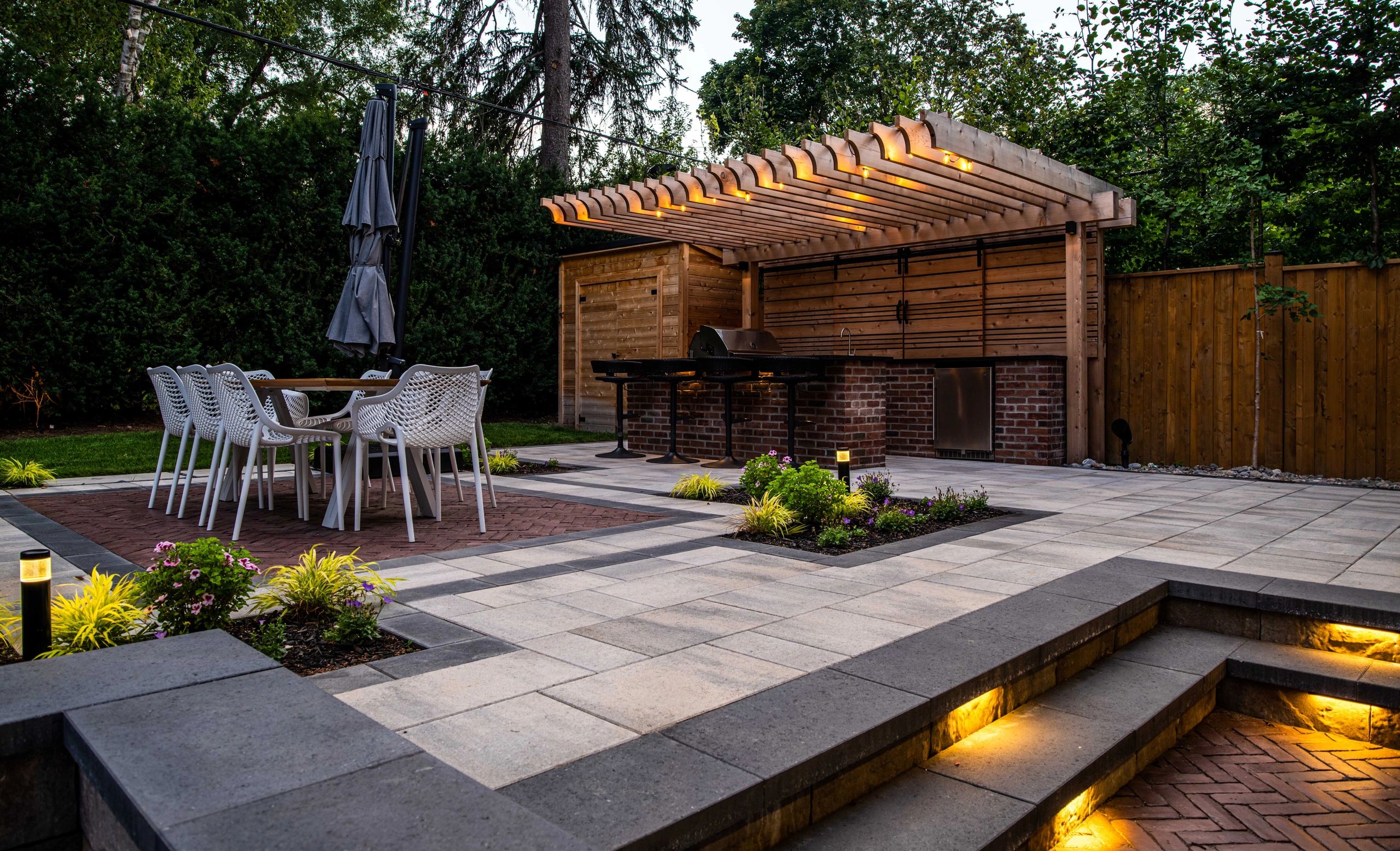 Modern outdoor patio with dining area and wooden pergola over a barbecue space.