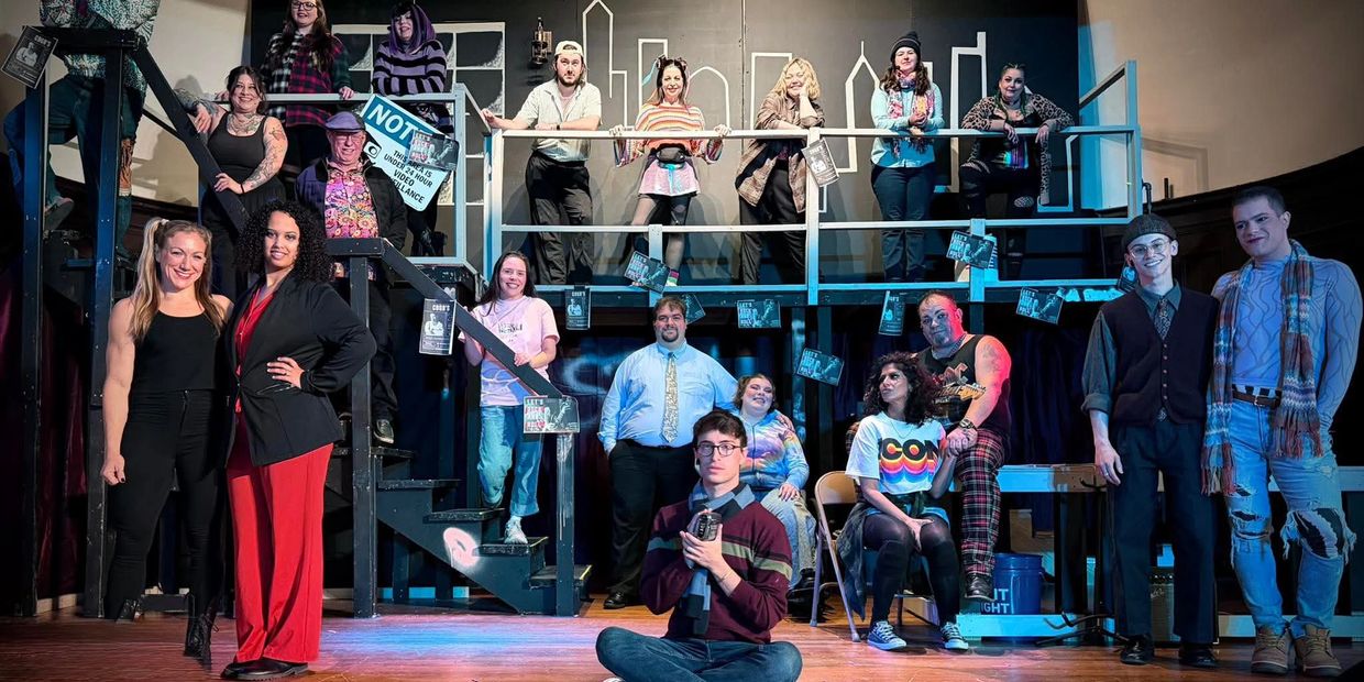 A diverse group on stage posing for a theatrical production photo.