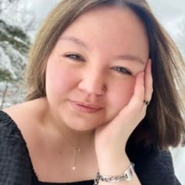 Woman with light brown hair resting her face on her hand outdoors.