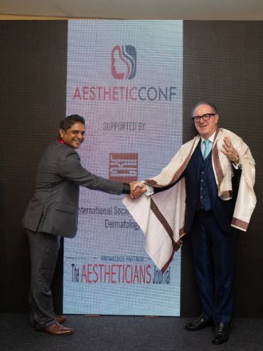Two men shaking hands at Aesthetic Conf event.