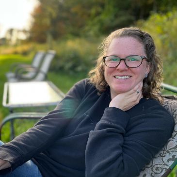 Smiling woman sitting outdoors on a bench.