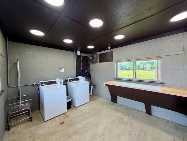 A small laundry room with washer, dryer, and a folding table by a window.