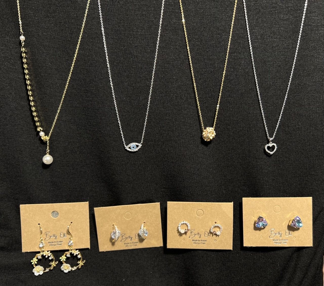 Elegant necklaces and earrings on display against a black background at The Peak in Albertville, MN