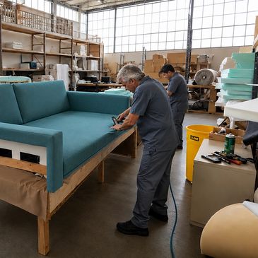 Workers upholstering a sofa in a workshop.