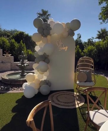 Outdoor baby shower decoration with balloons and chairs.