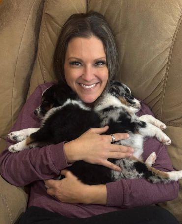 Woman happily hugging two sleeping puppies.