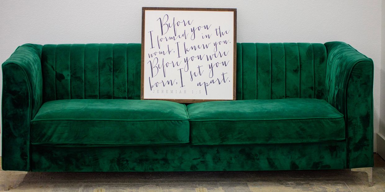 Emerald green velvet sofa with a framed inspirational quote on it.