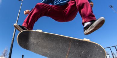 Skateboarder in a yellow beanie performing a trick mid-air against a clear blue sky.