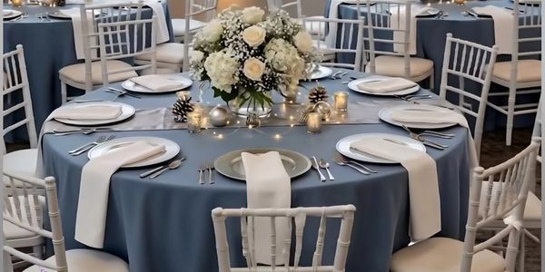 Elegant table setting with blue tablecloth and floral centerpiece.