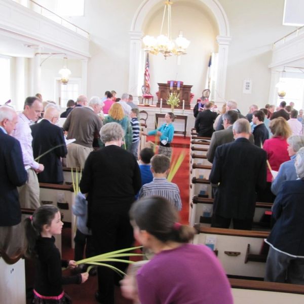 Congregation holding palm branches inside church.