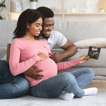 Pregnant woman and her partner are looking at an ultrasound of their baby