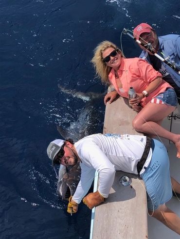 Three people posing with the fish from the boat