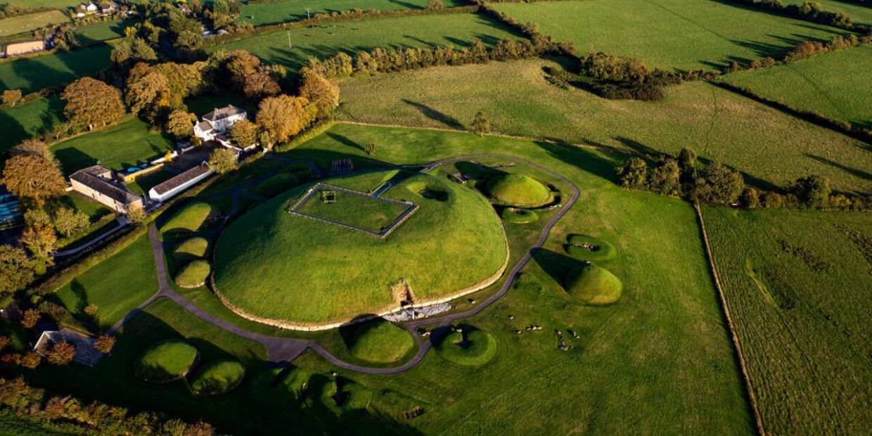 Aerial view of green ancient burial mounds surrounded by fields.