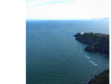 Coastal cliff with a lighthouse overlooking the ocean.