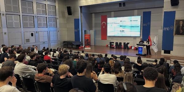 A speaker addressing a large audience in a university auditorium.